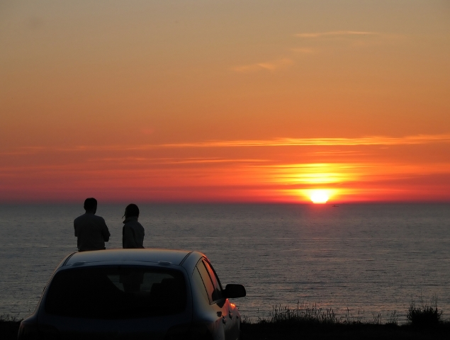 man and woman are watching a sunset