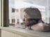 Young Mexican American woman looking out window with arms propped on window sill.  Shot on a Nikon d810 with a 58mm F:1.4 Nikkor lens. Slight detail extraction and mild vignetting added in post production